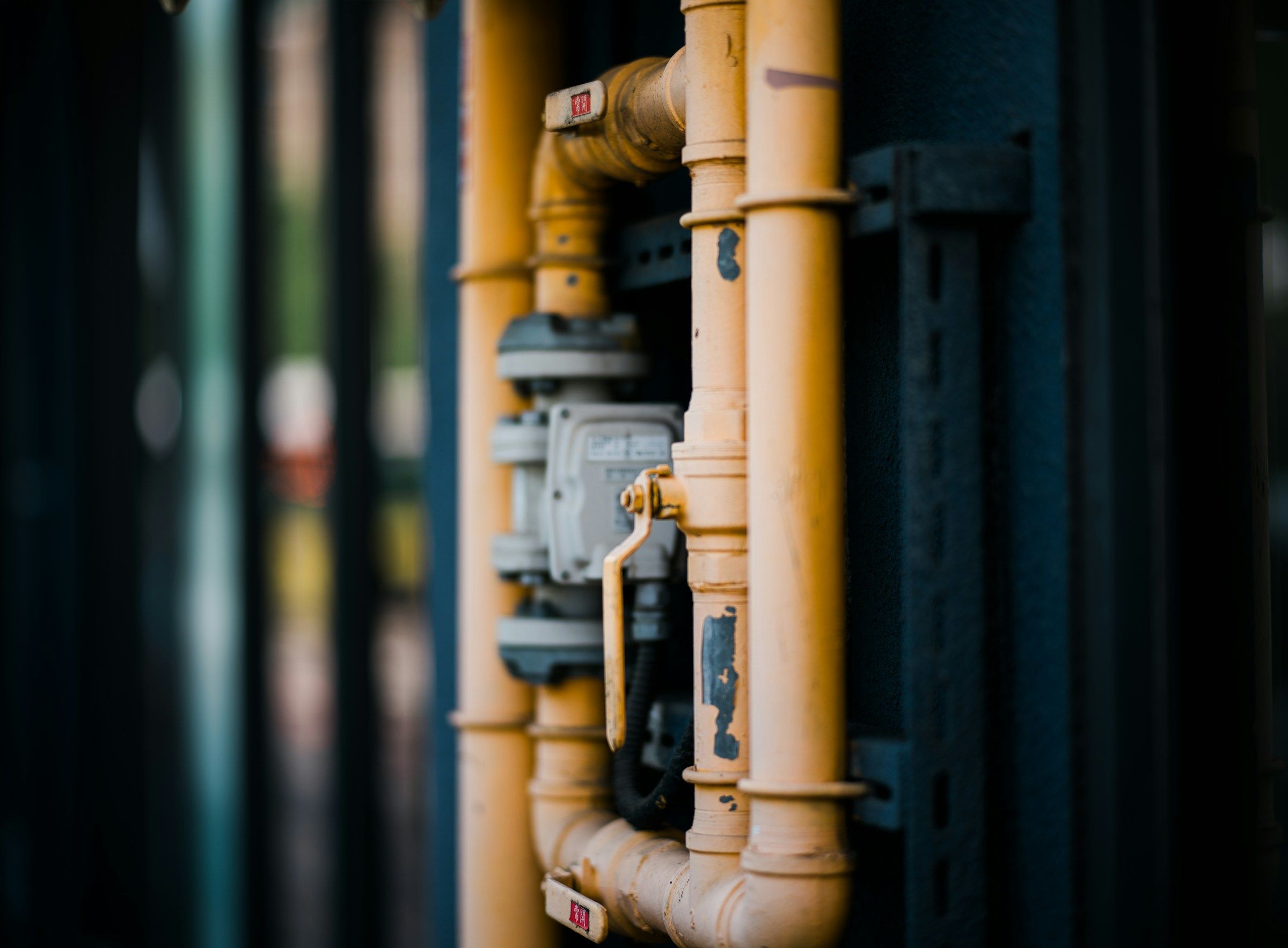 Cañerías amarillas de gas con válvula y manómetro en una instalación industrial.