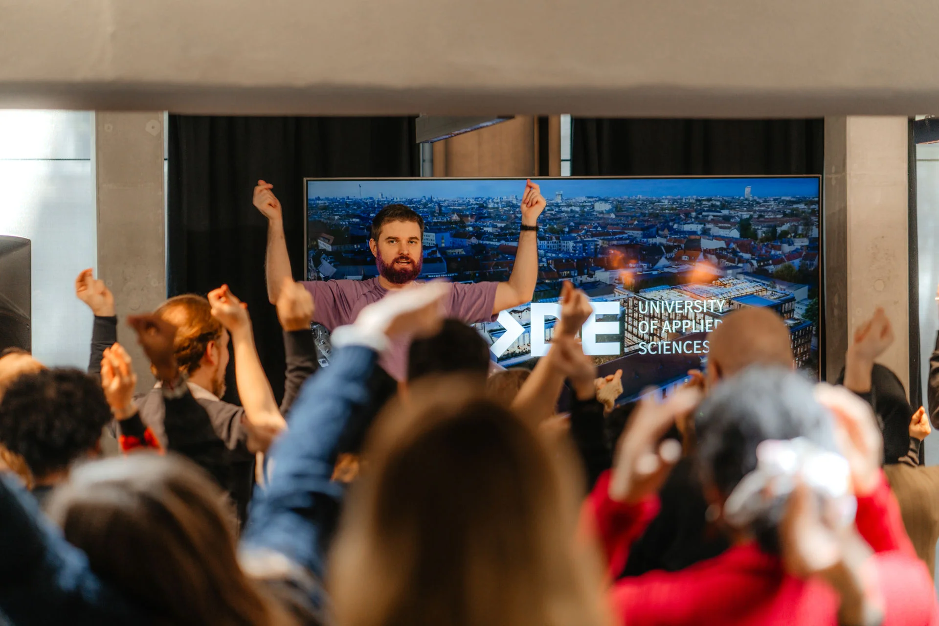 a man is standing in front of a crowd of people with his arms in the air .