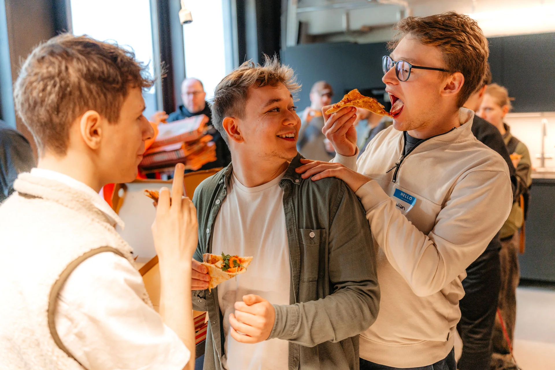 a group of young men are standing next to each other eating pizza .
