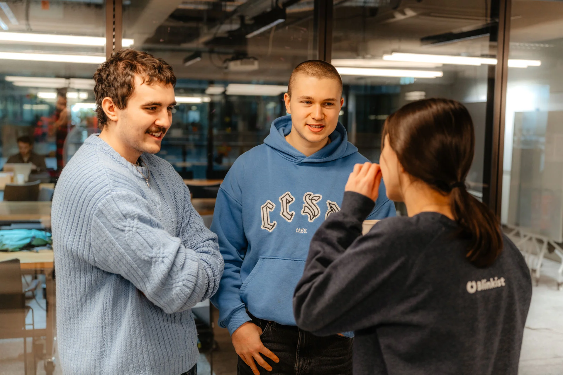 a group of young people are standing next to each other in a room and talking .