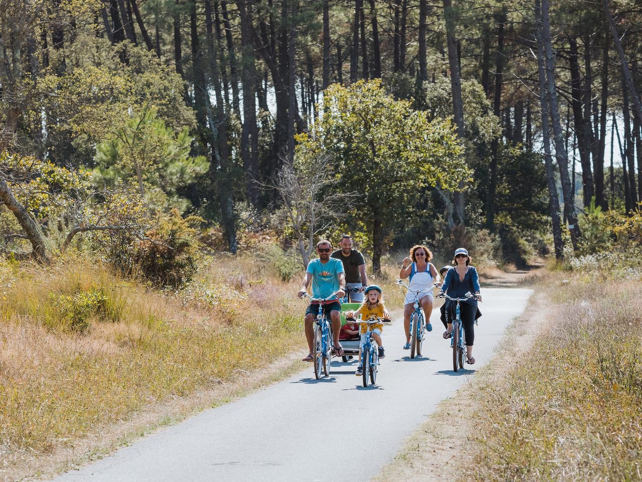 Famille à vélo sur une piste cyclable en forêt de pins