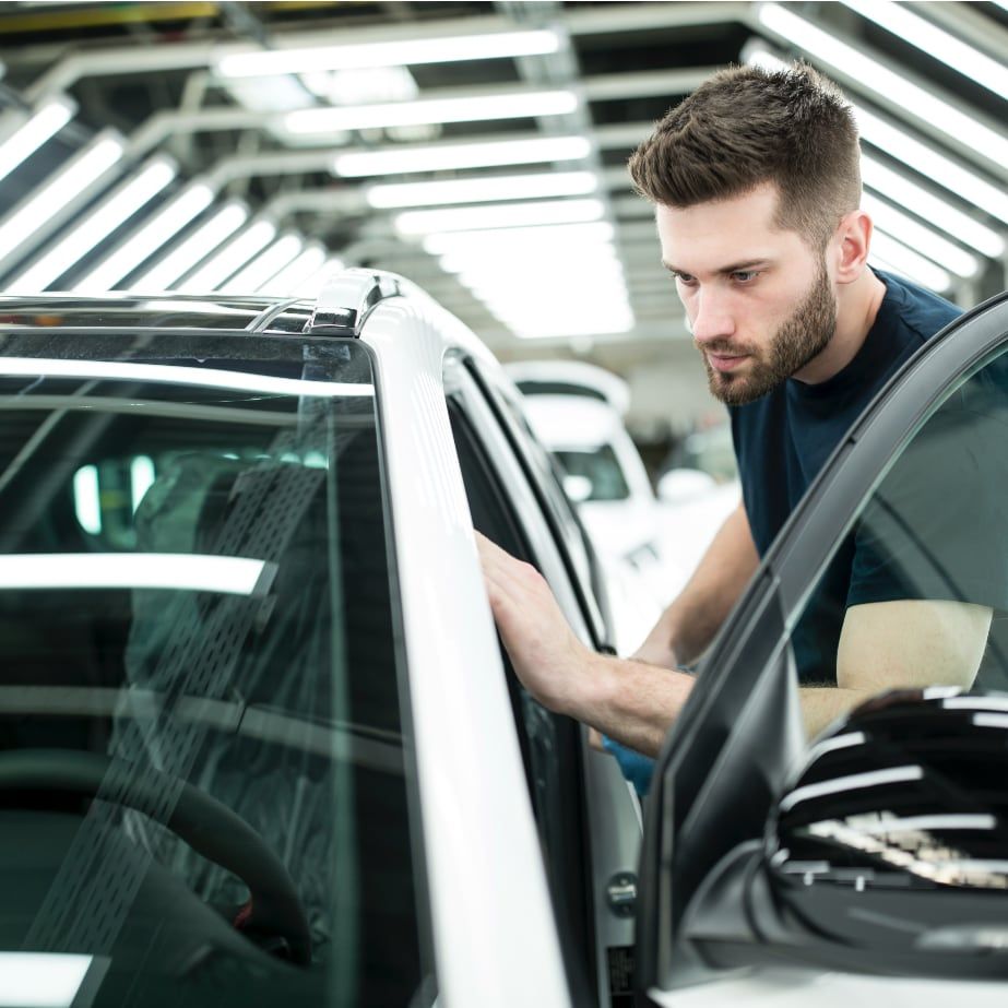 Young man examining car while using Drivvn eCommerce platform to research vehicle details in modern showroom