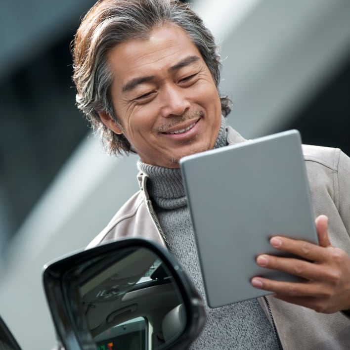 Man with tablet browsing automotive inventory on Drivvn-powered dealership website