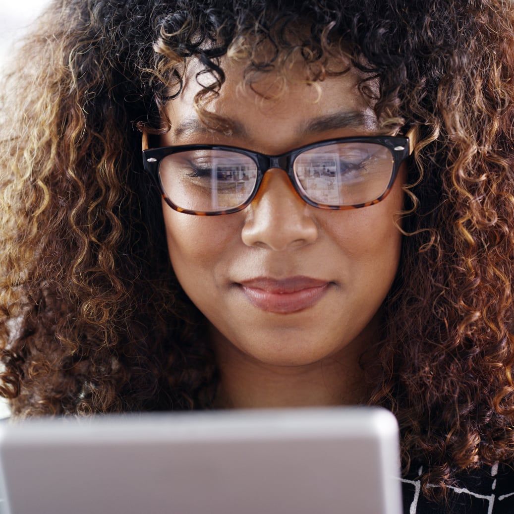 Woman with curly hair and glasses browsing Drivvn-powered automotive eCommerce storefront on mobile device