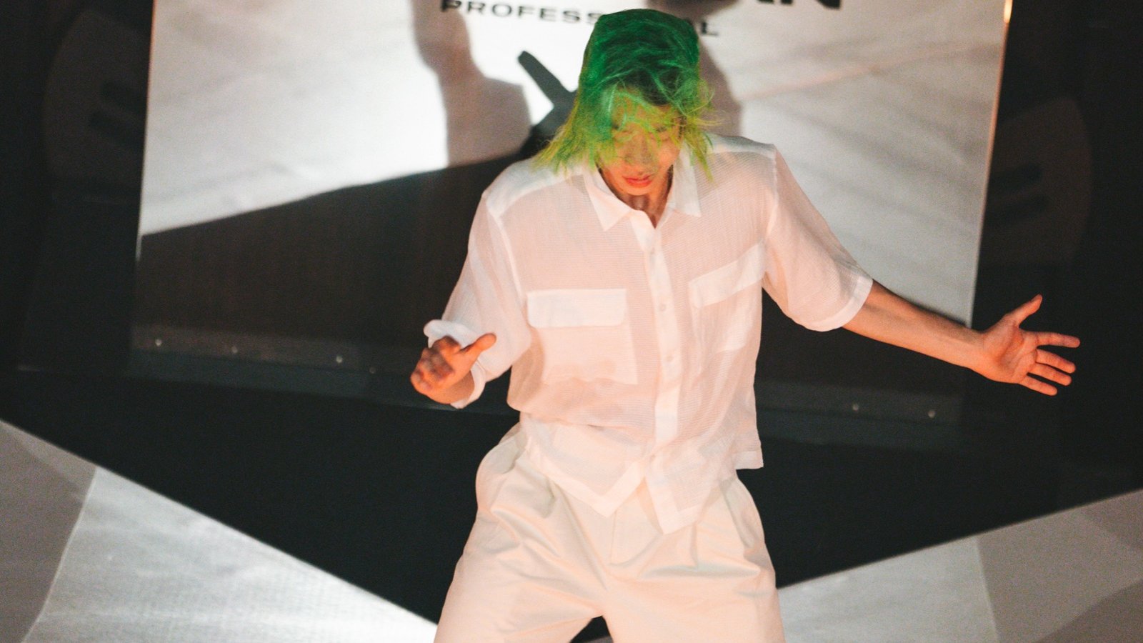 A performer on the runway in front of the mirror DJ booth with the Sebastian Professional mark