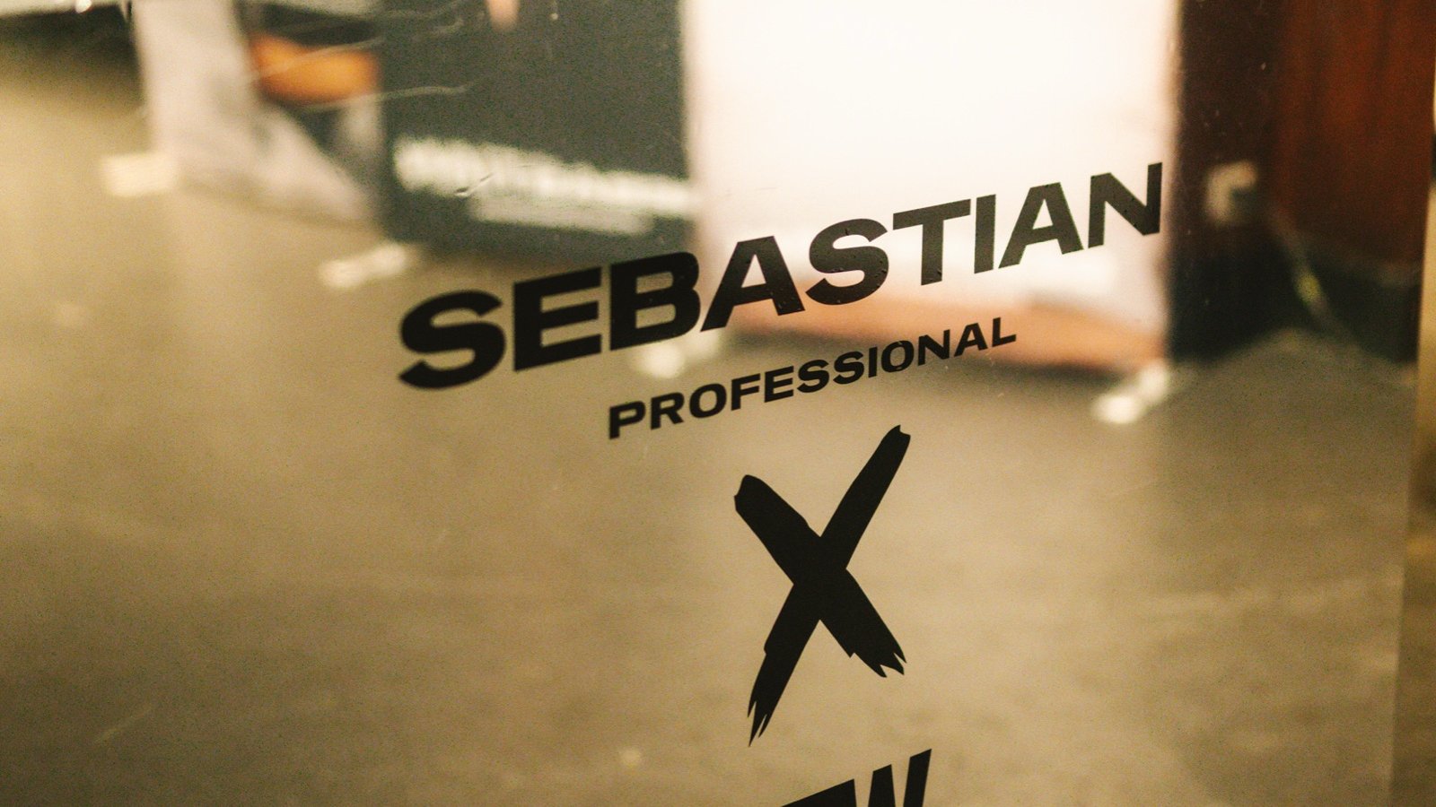 Mirror bar with the Sebastian Professional × AFW mark, glasses on a small table behind