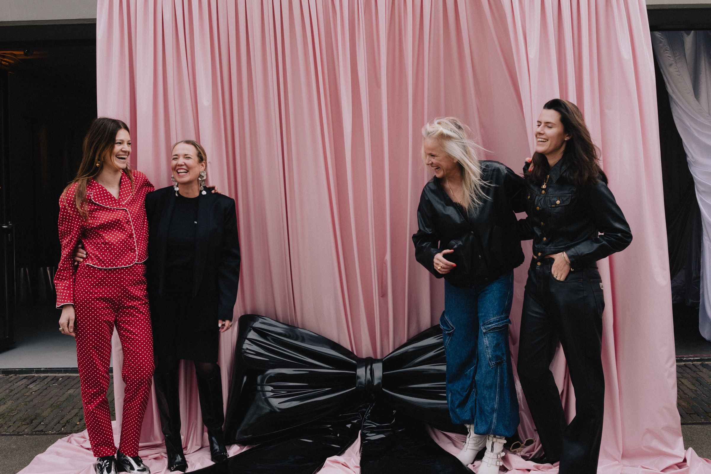 The core City Dressers team in front of the pink drape, the black patent bow at their feet