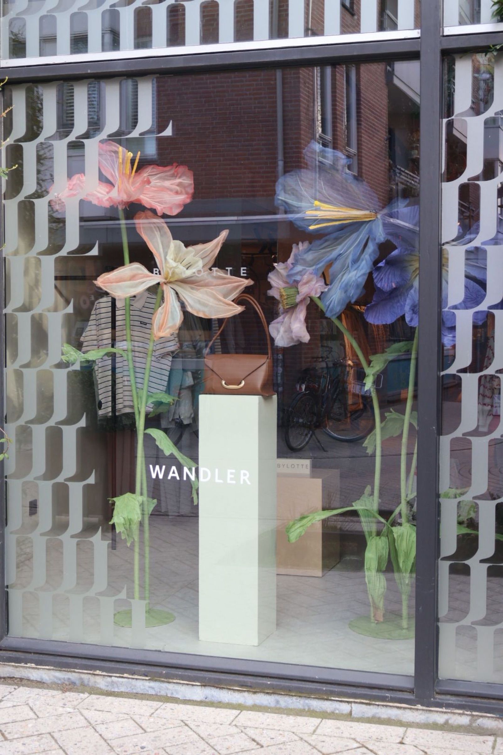 The By Lotte shop window with oversized fabric flowers around a Wandler plinth