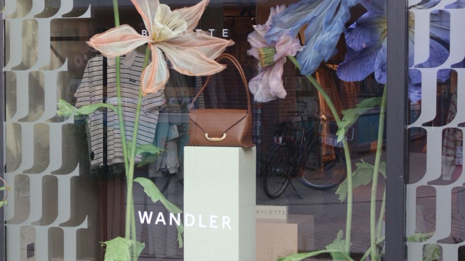The By Lotte shop window with oversized fabric flowers around a Wandler plinth