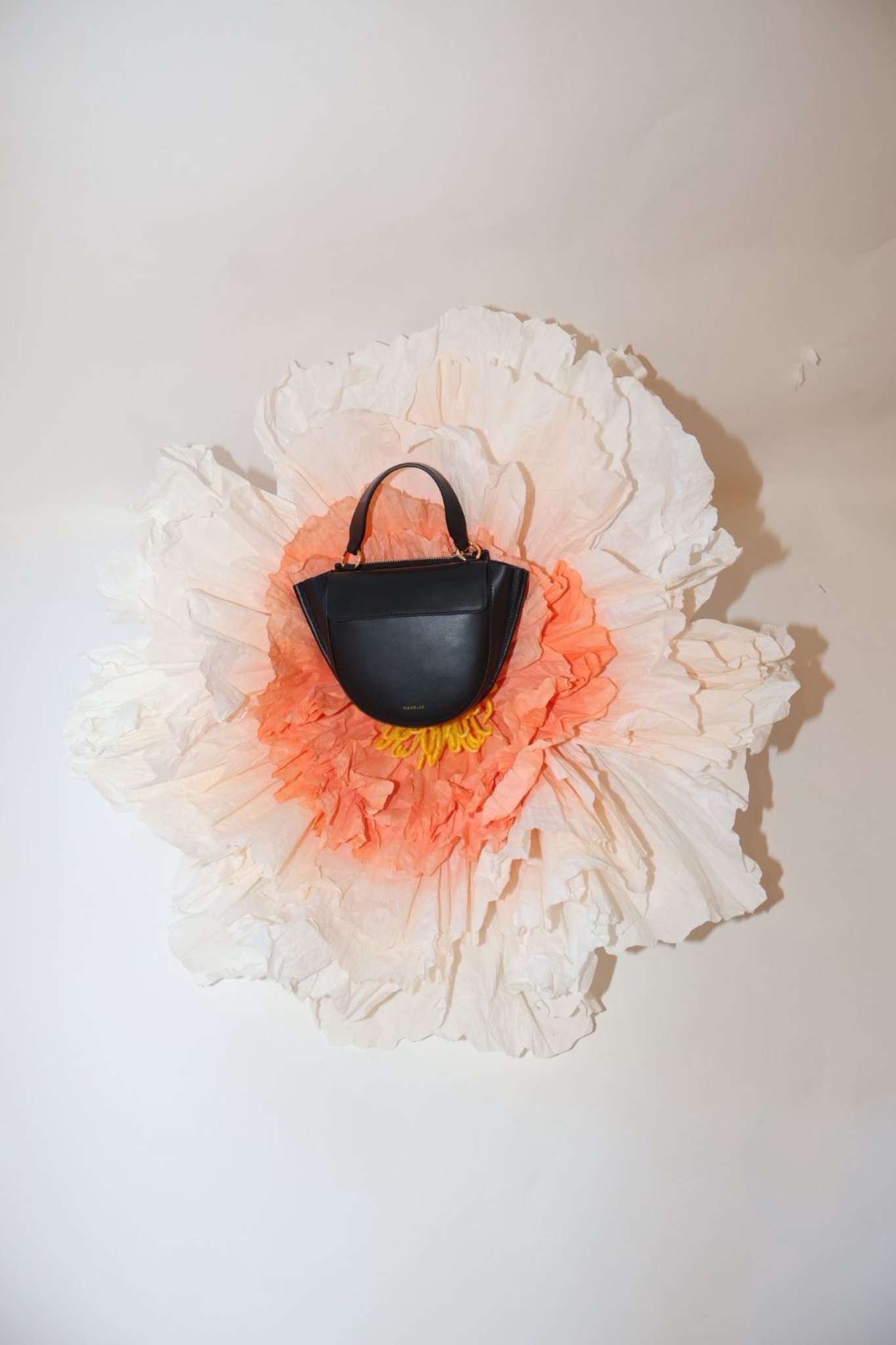 Oversized fabric flowers around a Wandler bag display at By Lotte