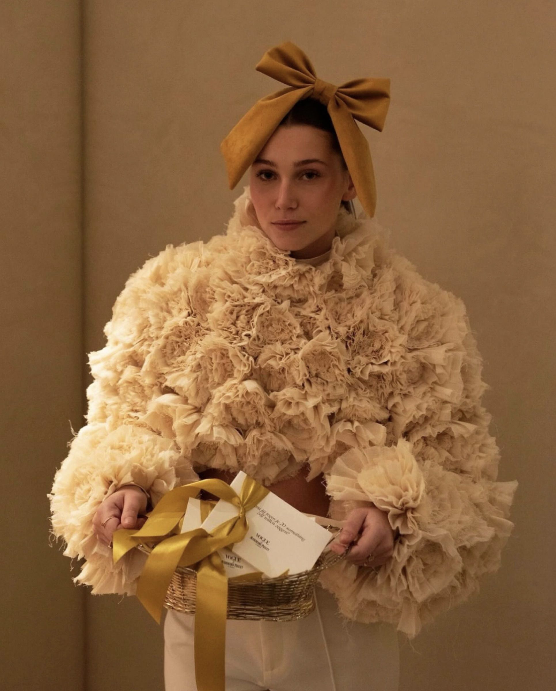 A guest wearing a gold velvet bow in her hair, holding a gift with a gold ribbon