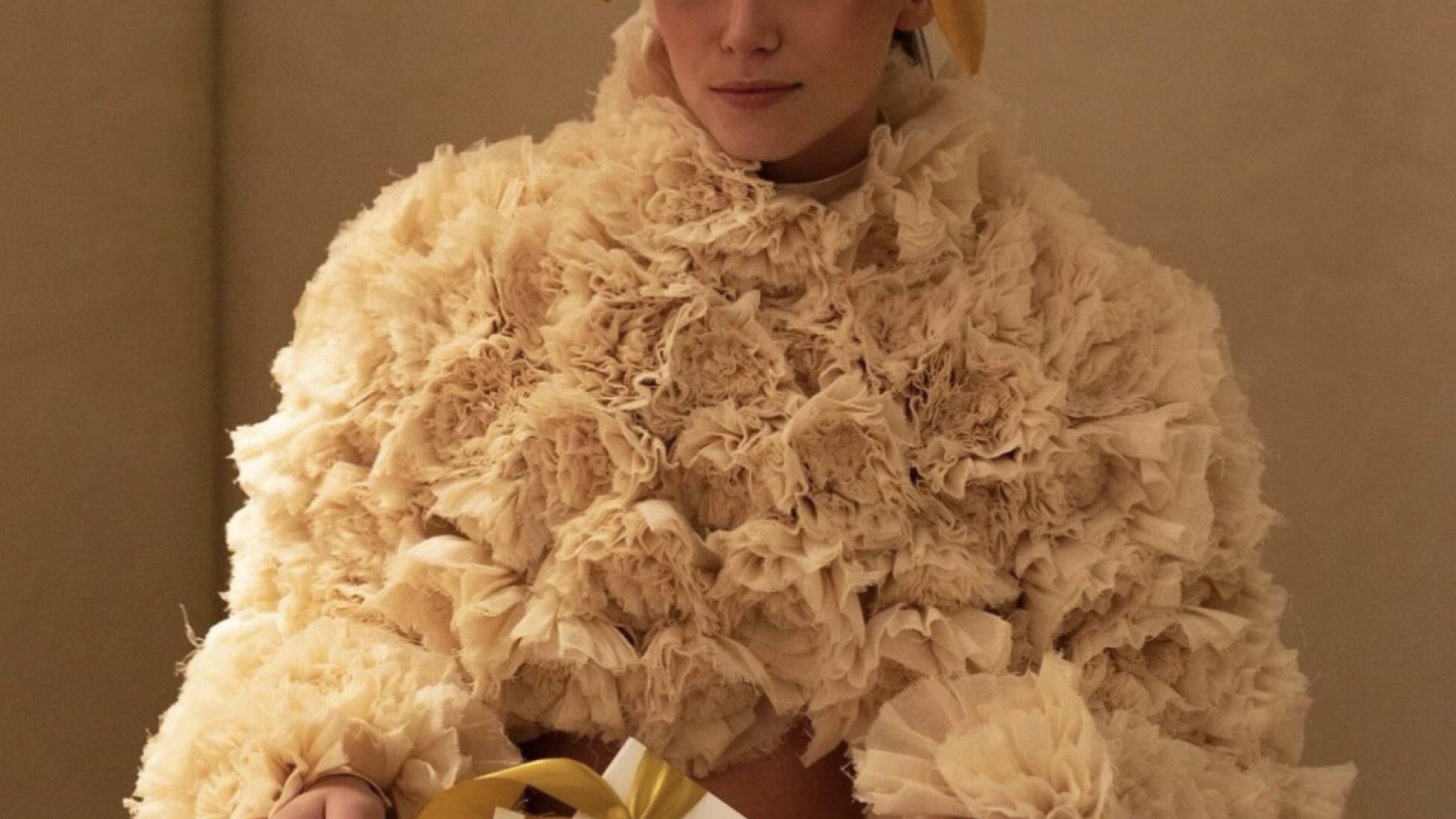 A guest wearing a gold velvet bow in her hair, holding a gift with a gold ribbon