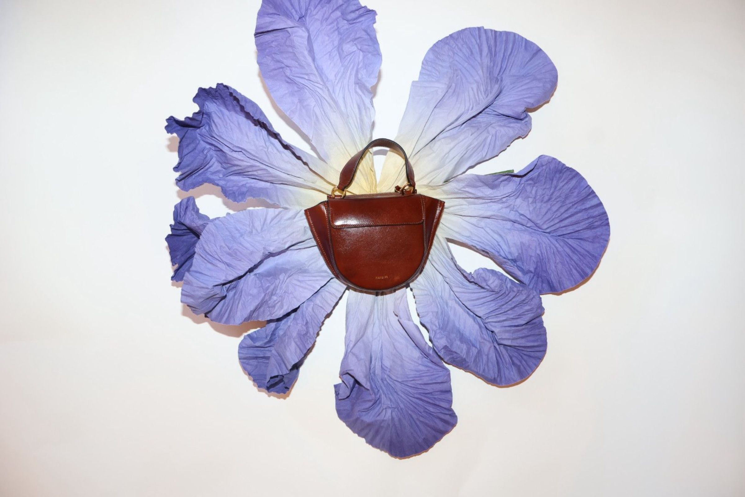 Oversized fabric flowers around a Wandler bag display at By Lotte