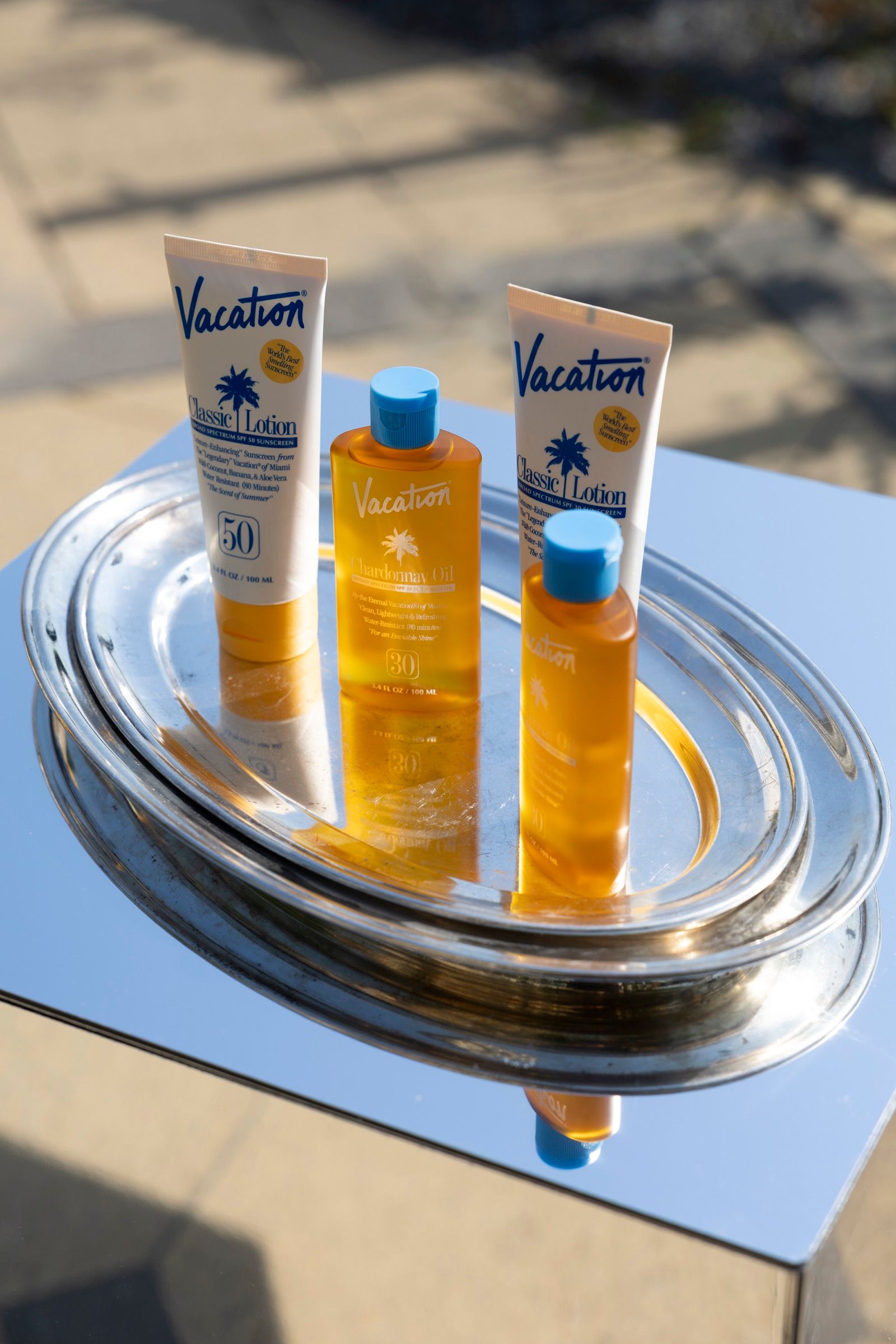 Sunscreen bottles on a silver tray on a mirror trolley, in the sun