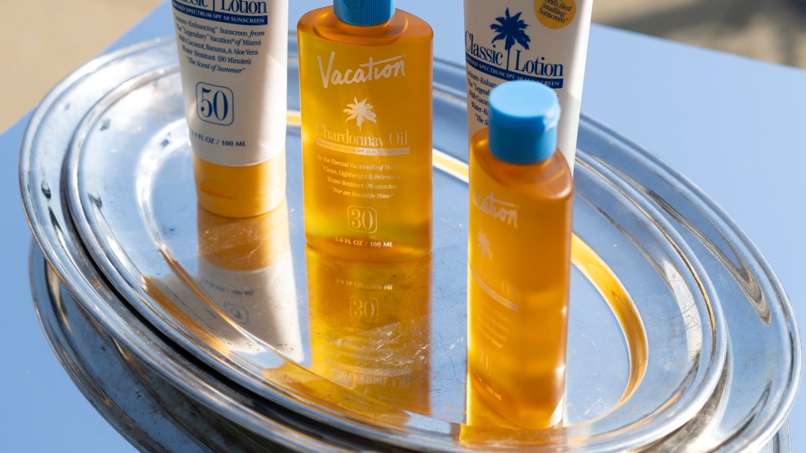 Sunscreen bottles on a silver tray on a mirror trolley, in the sun