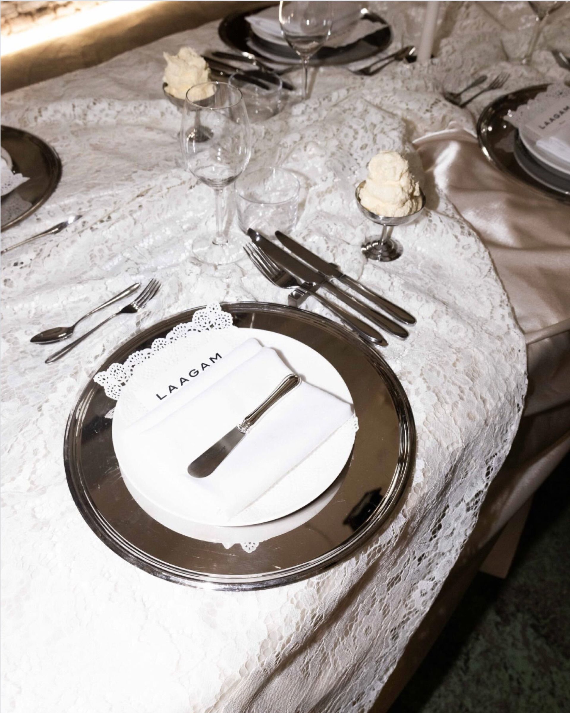 Mirror charger plates and glassware on a lace tablecloth for the Laagam dinner