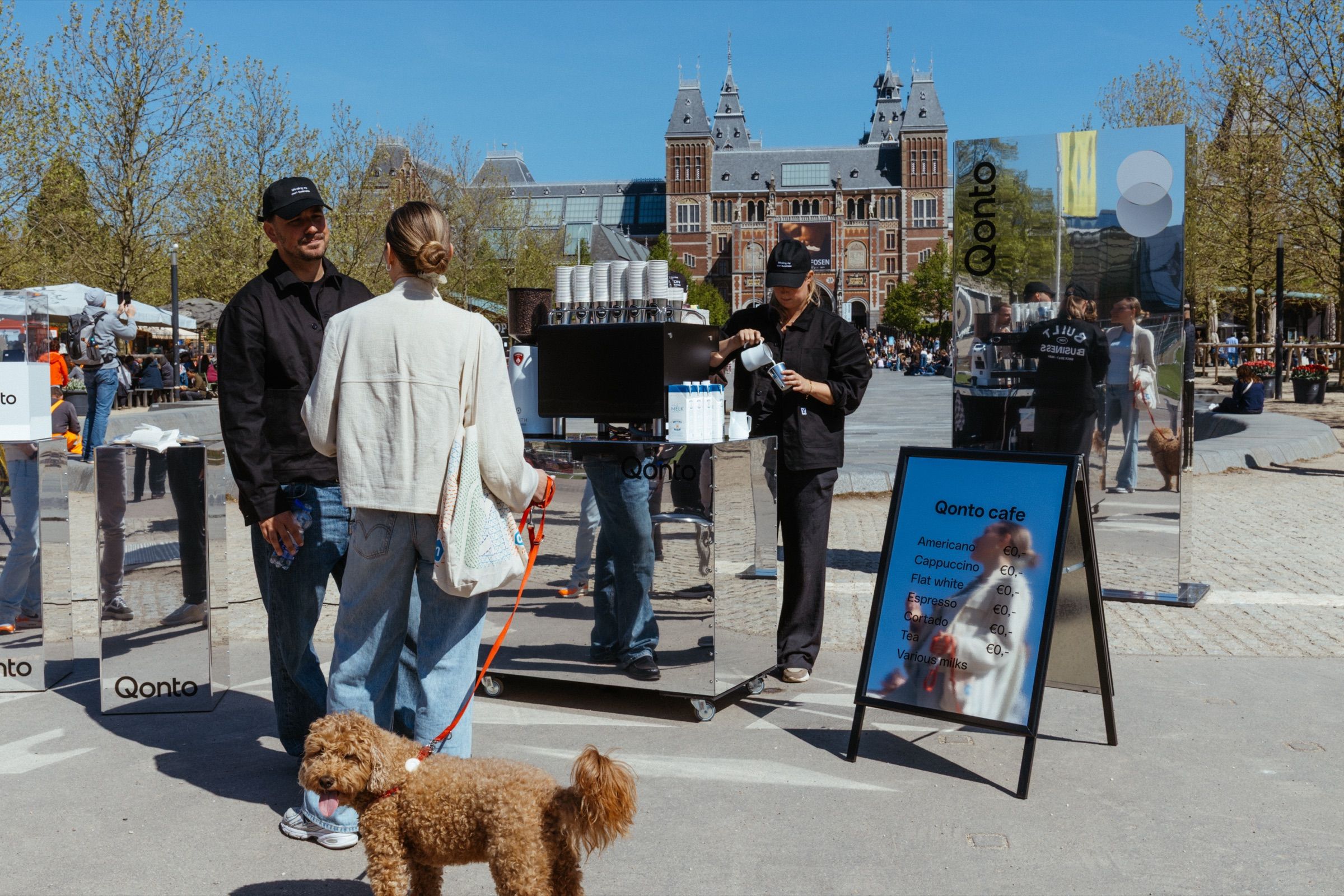 A mirror coffee cart and the Qonto café sign on Museumplein, the Rijksmuseum behind