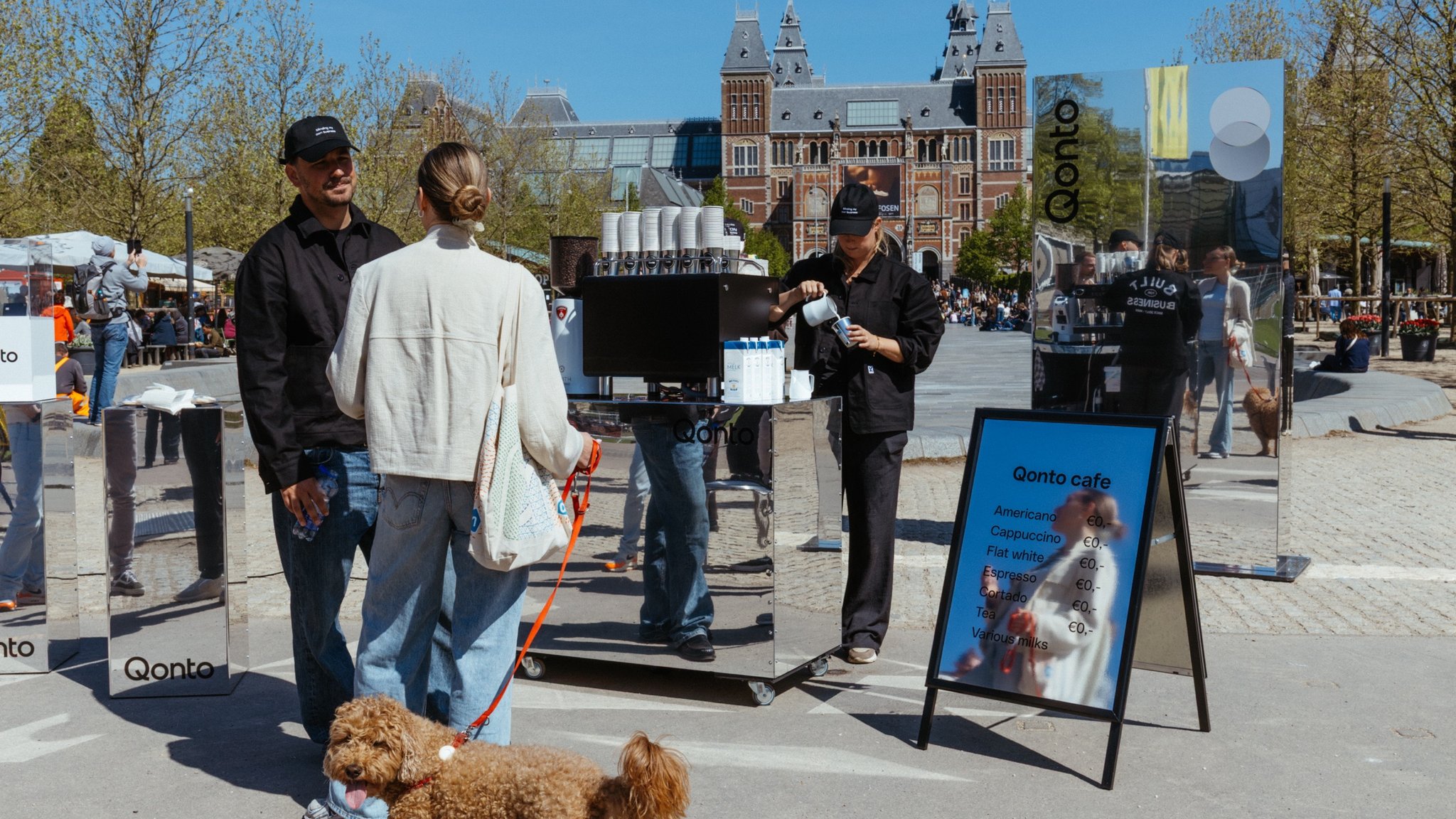 A mirror coffee cart and the Qonto café sign on Museumplein, the Rijksmuseum behind