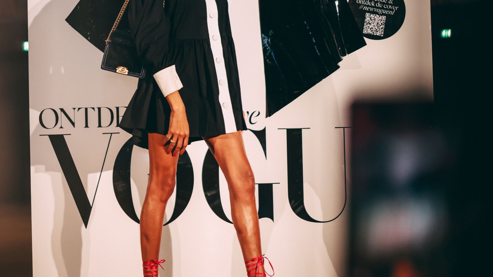 A model in black and white in front of the VOGUE box and its giant black bow