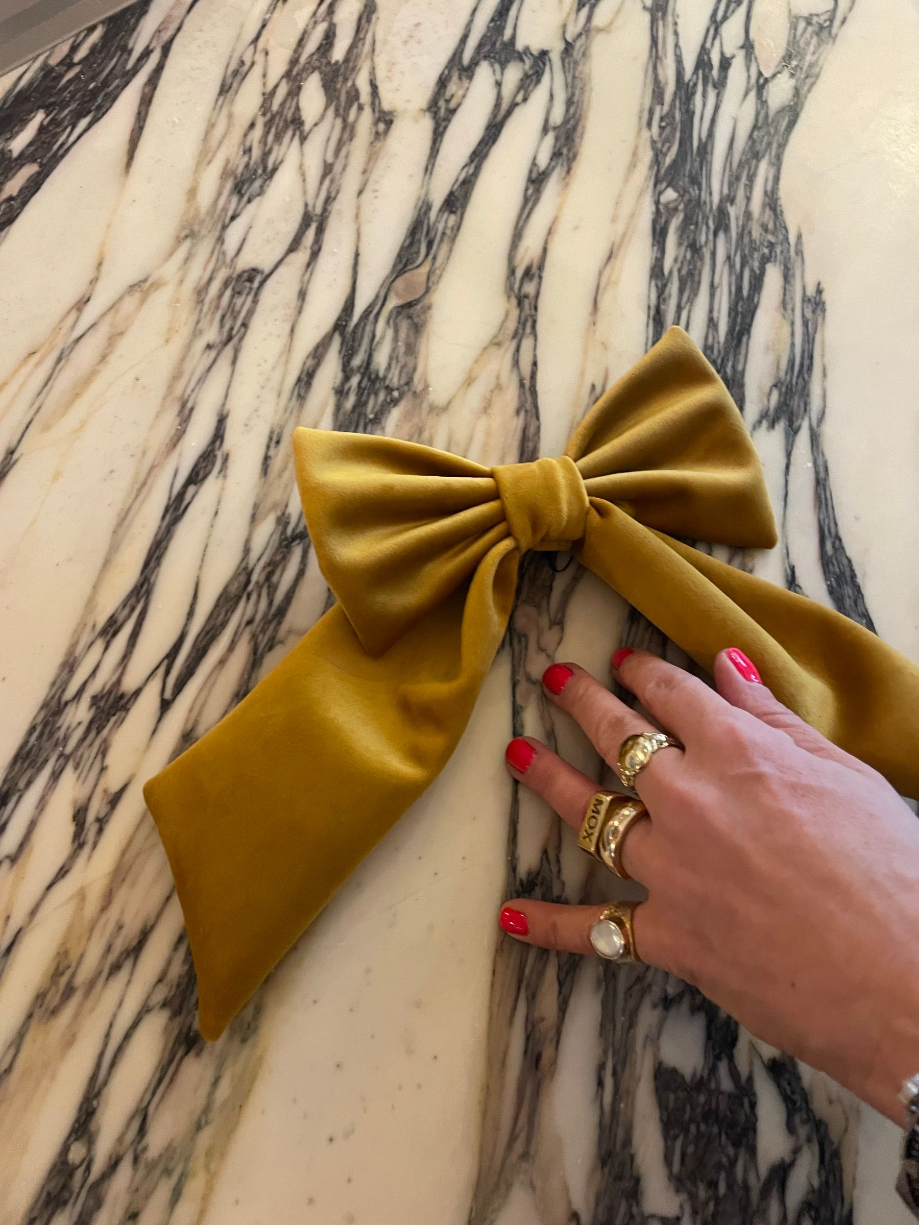 A hand-sized gold velvet bow on a marble table