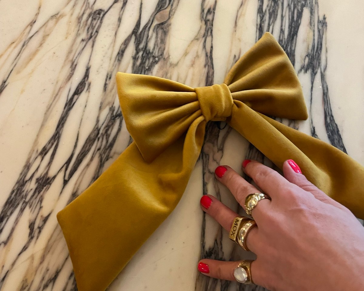 A hand-sized gold velvet bow on a marble table