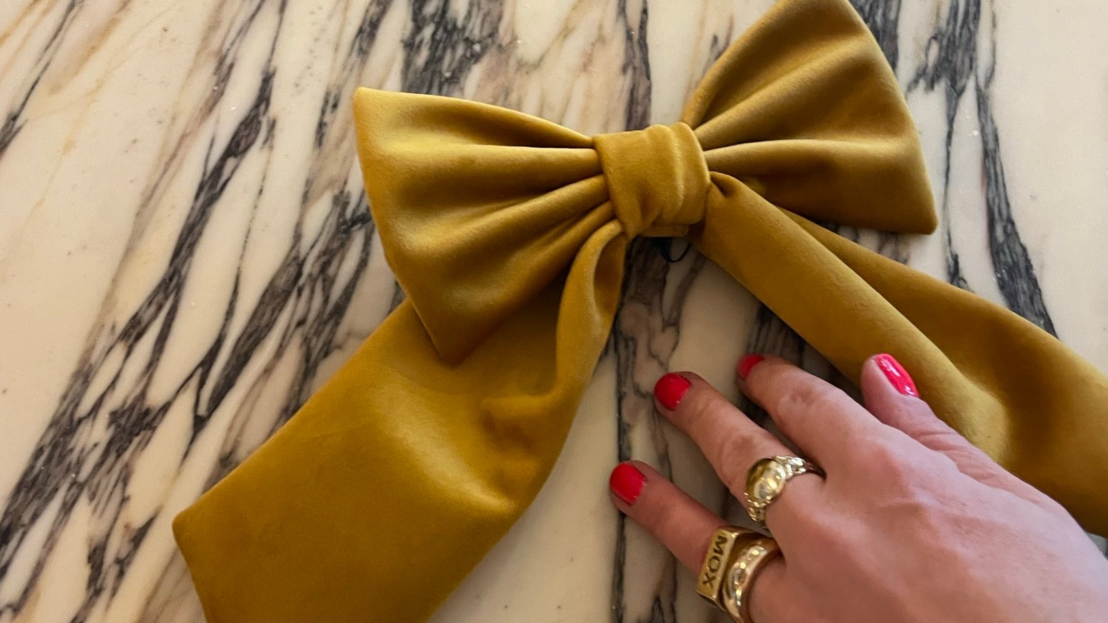A hand-sized gold velvet bow on a marble table