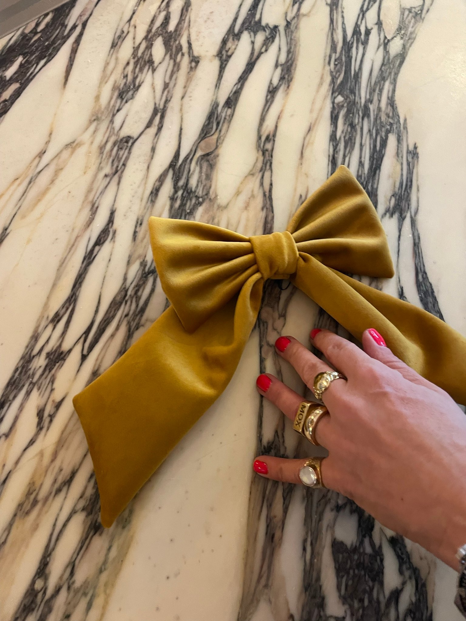 A hand-sized gold velvet bow on a marble table