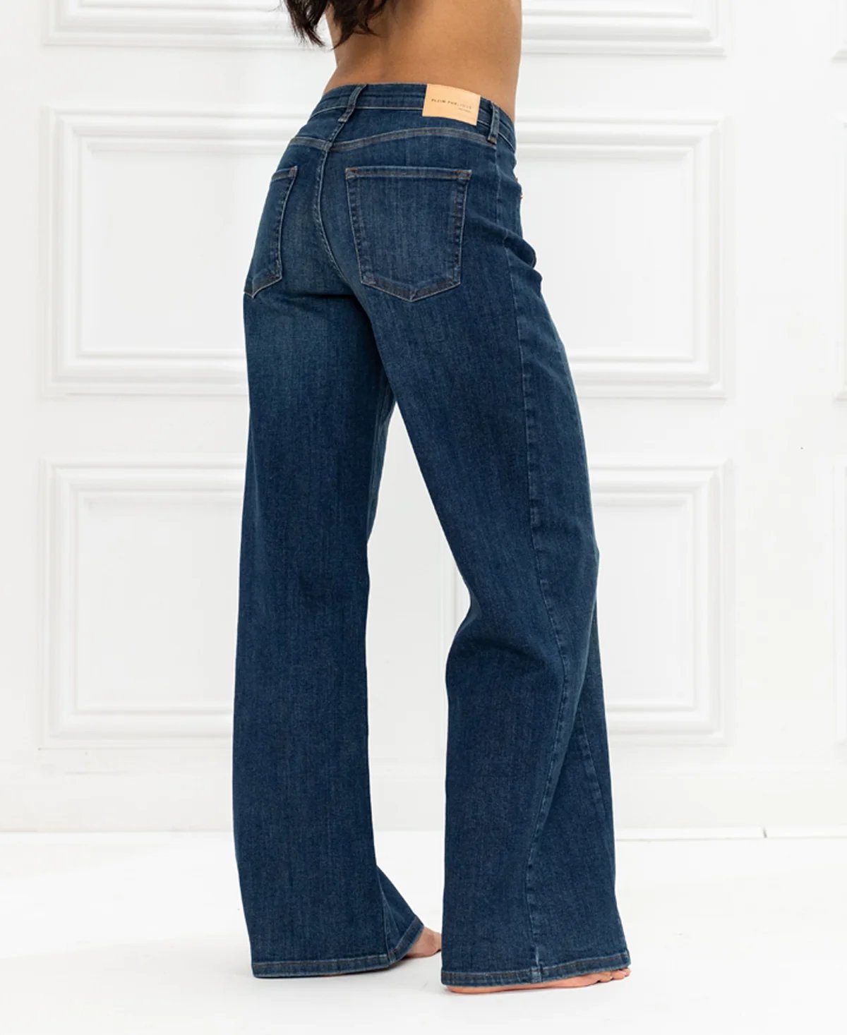 A person from behind wearing dark blue, wide-leg jeans.