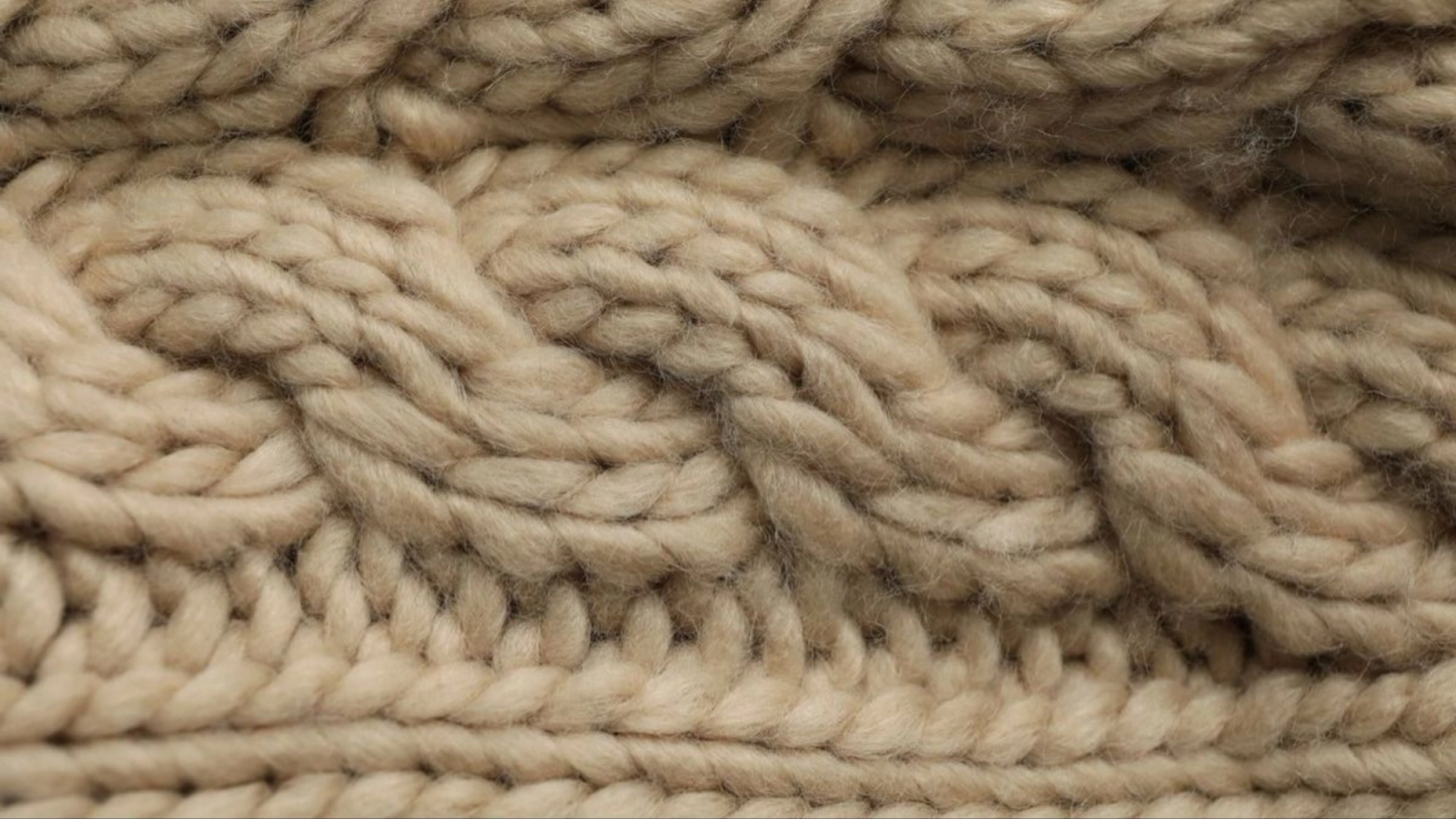 Close-up of beige cable-knit fabric.