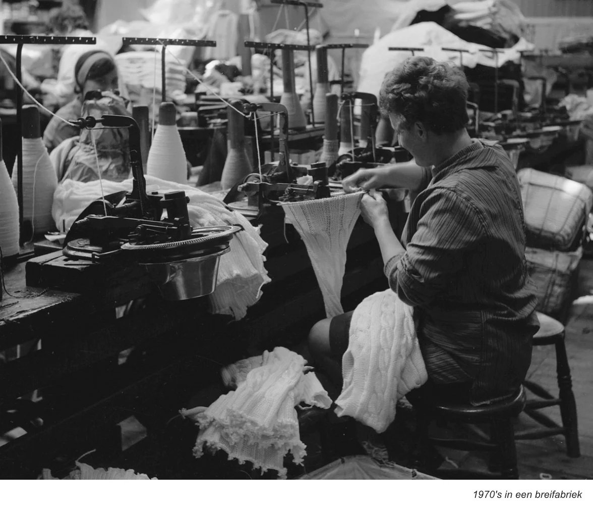 Schwarz-Weiß-Foto einer Frau, die in einer Fabrik der 1970er Jahre an einer Strickmaschine arbeitet.