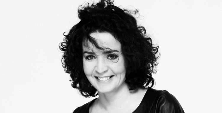 Black-and-white portrait of a smiling woman with dark, curly hair.