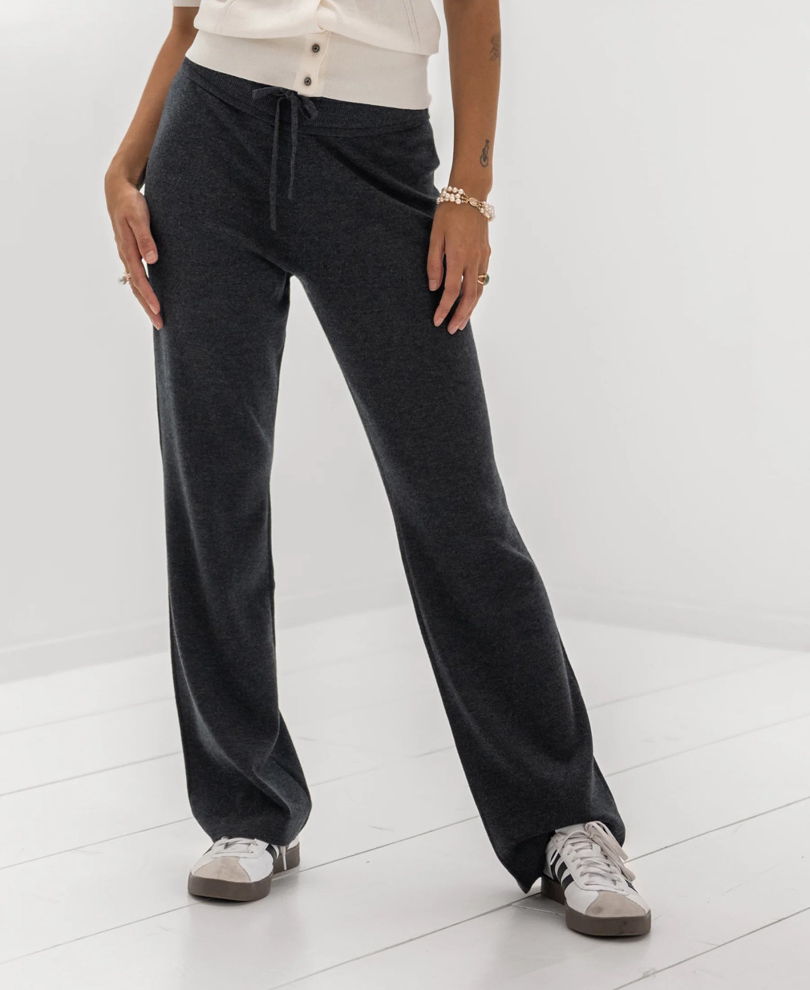 Dark grey drawstring sweatpants and white sneakers.