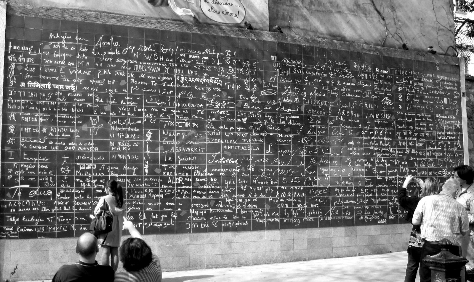 A black-and-white photo of the Wall of Love in Paris, displaying 