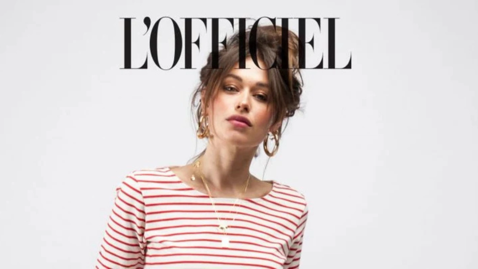 A woman wearing a red-and-white-striped top and gold jewelry, with the text 