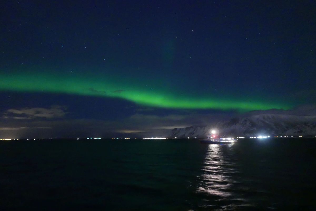 The northern lights with a boat's spotlight in the distance