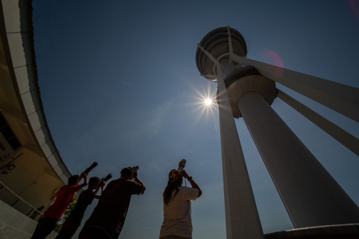 A man photographing a near-total solar eclipse with a telephoto lens