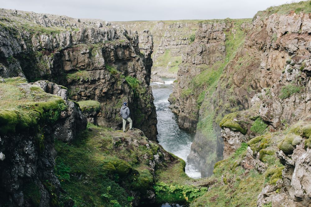 A solo traveler in a rugged Icelandic rocky landscape on a sunny day after a challenging hike