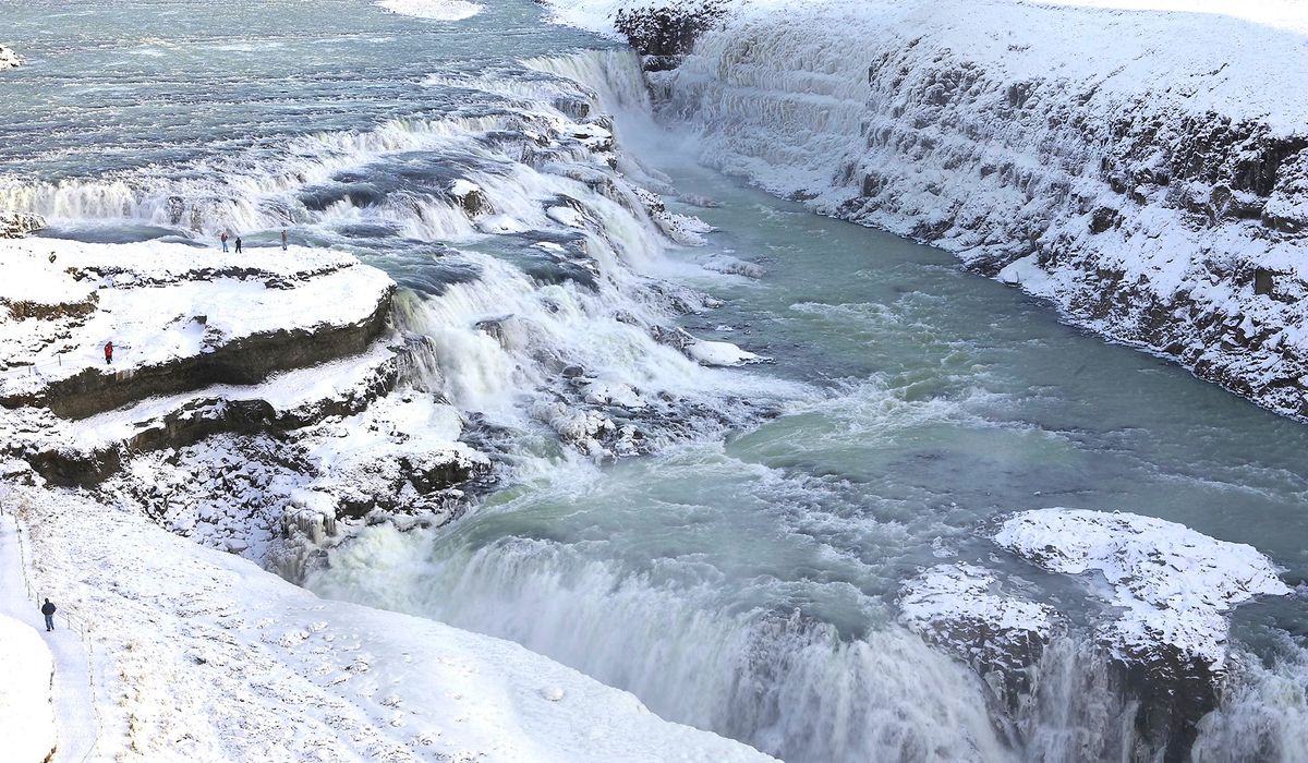 Gullfoss waterfall pouring into its canyon, with snow covering the rocks and banks around it