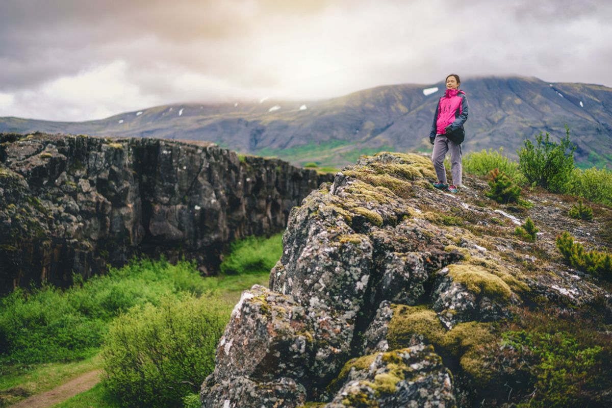 A woman traveler hiking across Iceland’s summer landscape, exploring its unique natural scenery