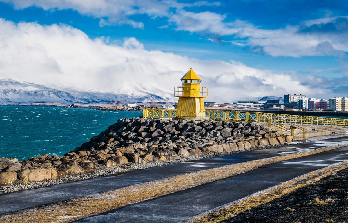 Lighthouse and stone embankment of Reykjavik against the backdrop of mountain