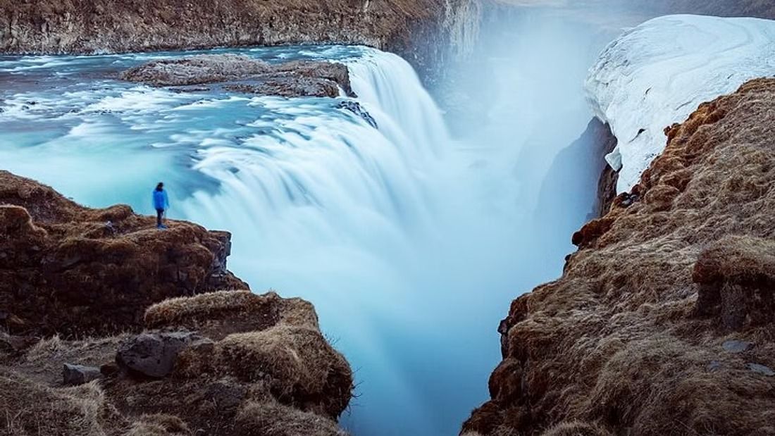 A visitor standing above Gullfoss in deep winter snow