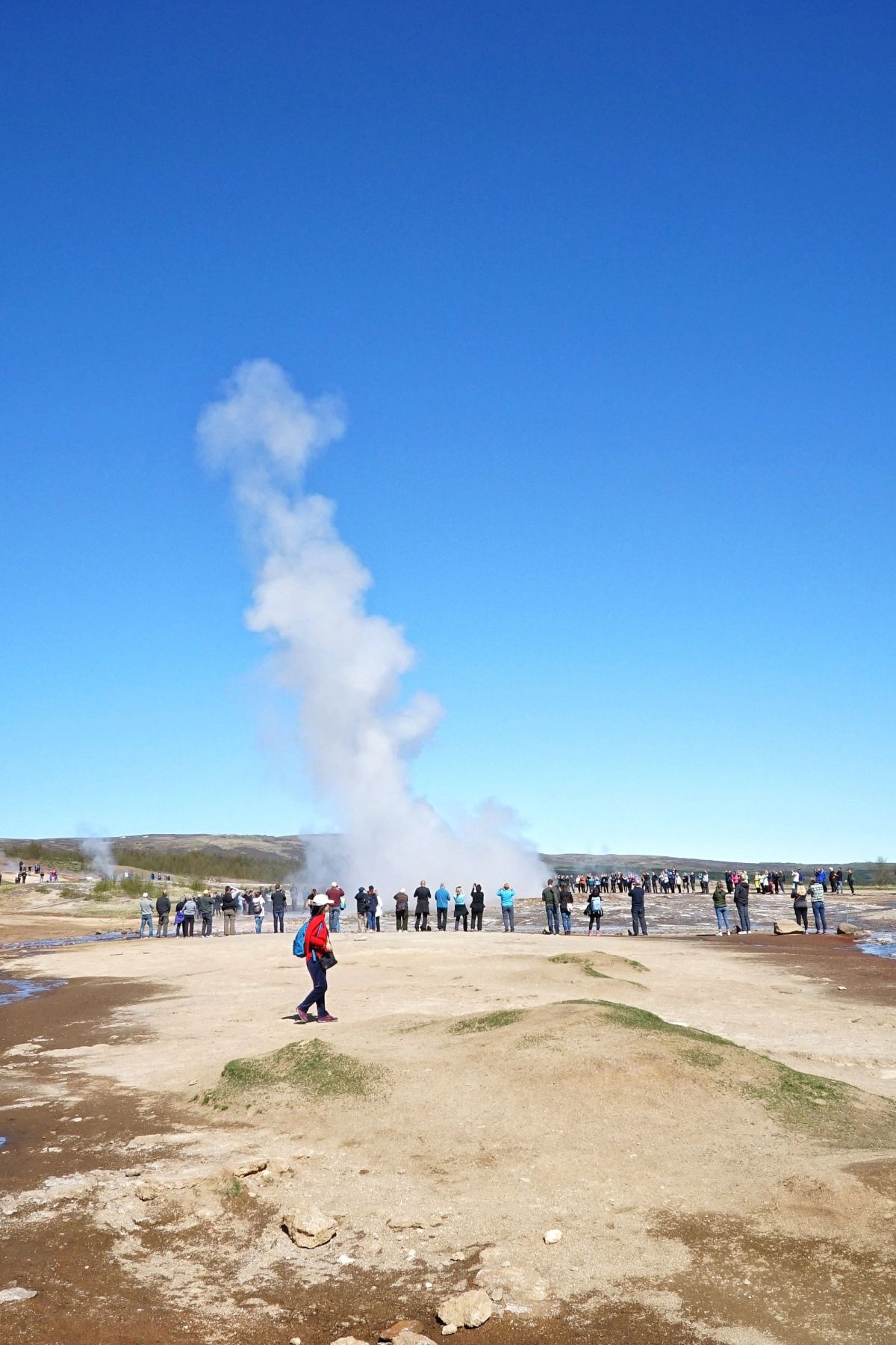 Strokkur geyser erupting in front of a crowd of visitors