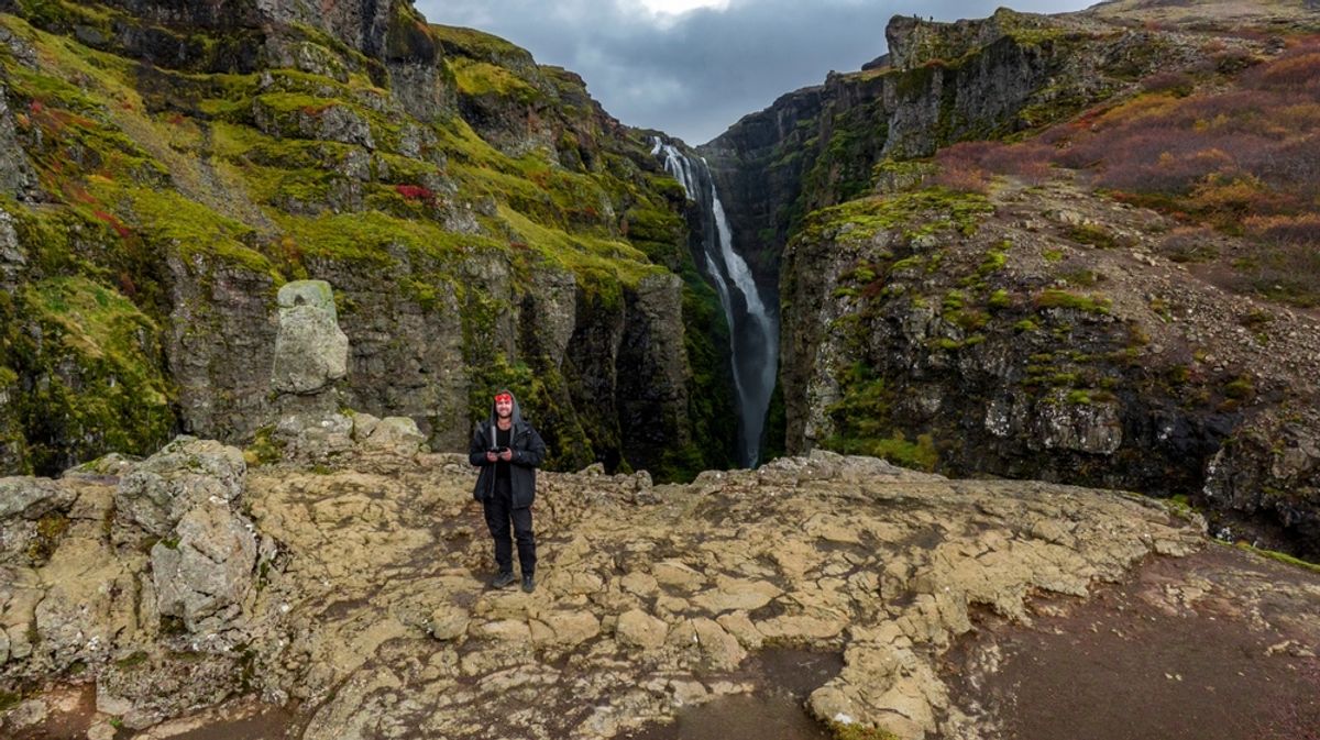 Man taking a picture with drone at Glymur Waterfall in iceland