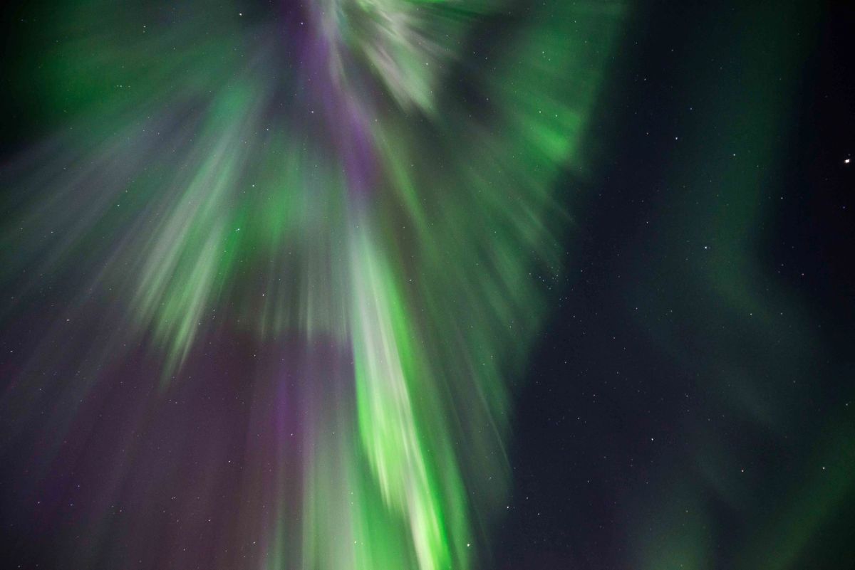 A close-up of a purple and green aurora corona