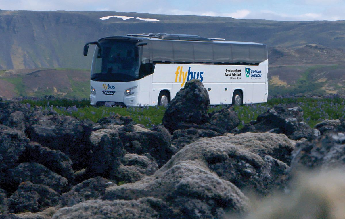 A tour coach on the road across an Icelandic lava field