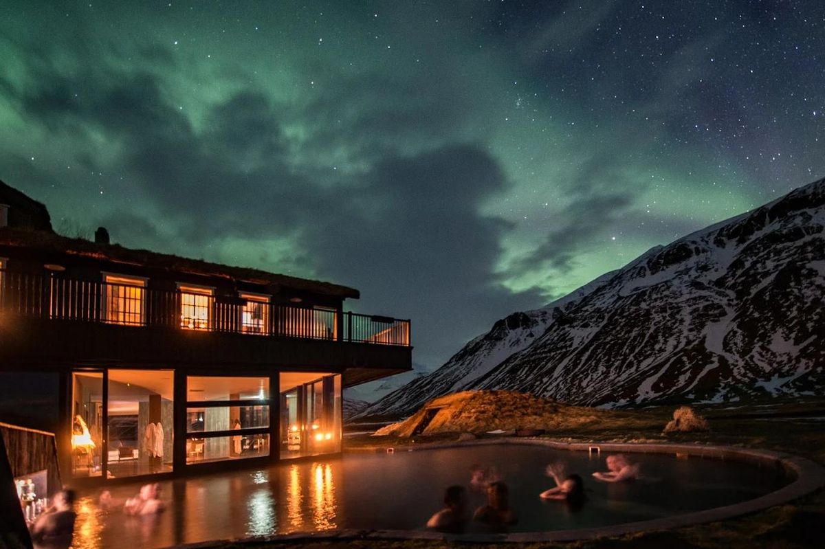 A lodge with an outdoor hot tub under the northern lights
