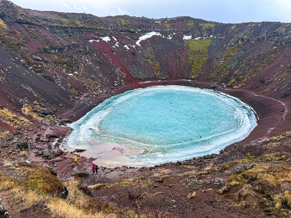 Kerid volcanic crater lake with frozen turquoise water and red caldera walls