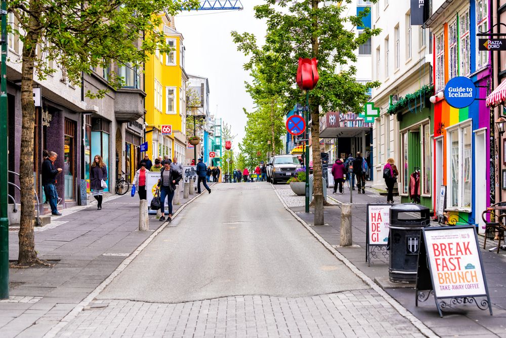 Laugavegur shopping street in downtown Reykjavík, lined with shops, signs, and tourist information