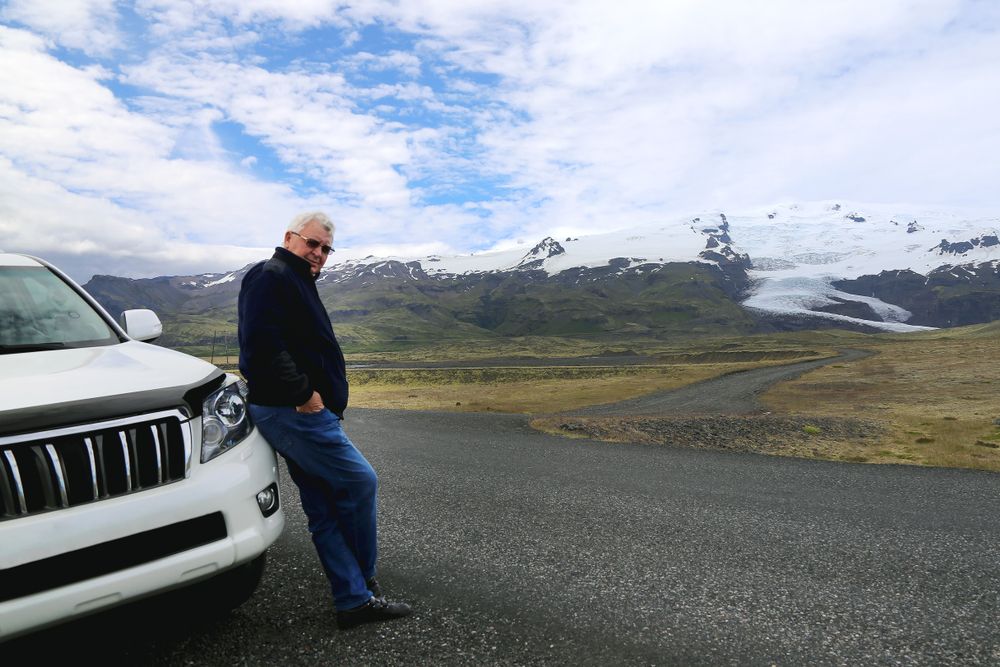 Vehicle traveling a two-lane Icelandic highway through open countryside at dusk