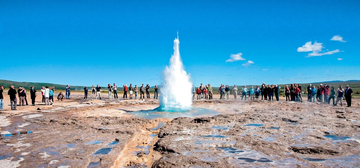 Strokkur erupting with a wide crowd of visitors watching